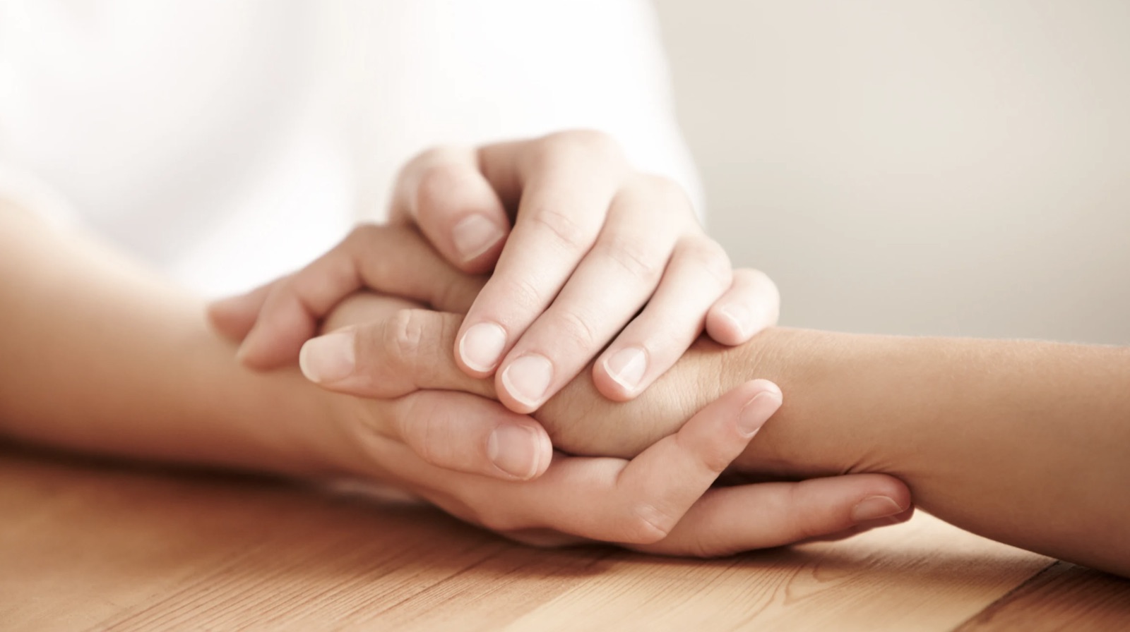 One person holding another's hands across a table.