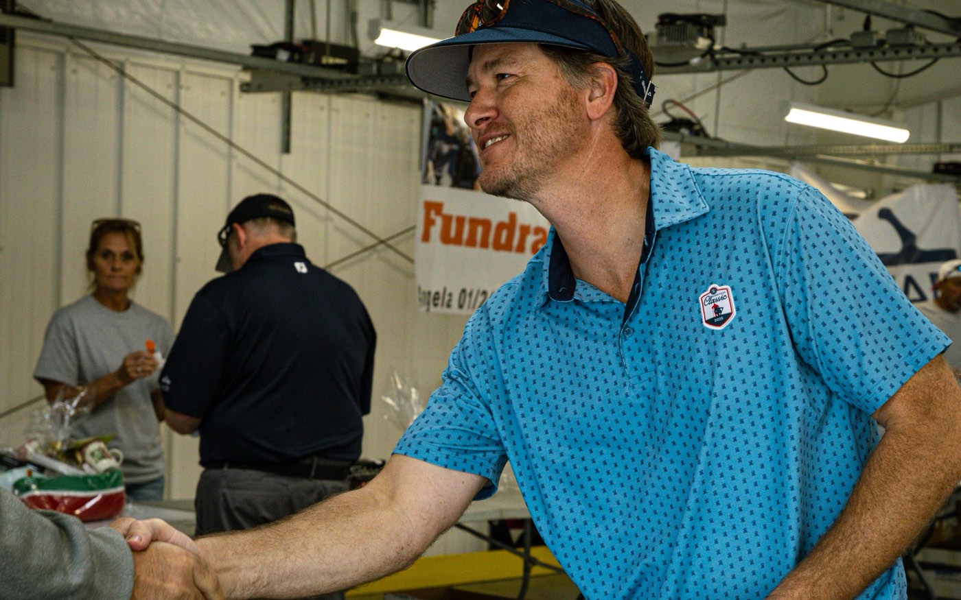 A supporter shaking hands beside the raffle table at an AES Cancer Foundation fundraiser.